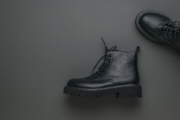 A pair of stylish black leather boots on a dark gray background.