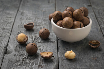 A small bowl of macadamia nuts on a wooden table.