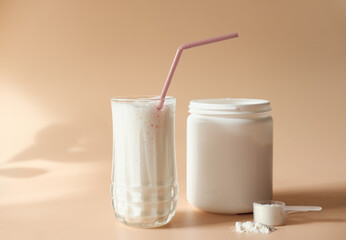 whey drink in a high glass. whey protein vanilla cocktail. a jar with protein powder and a scoop of powder on a table. morning drink for health and beauty - obrazy, fototapety, plakaty