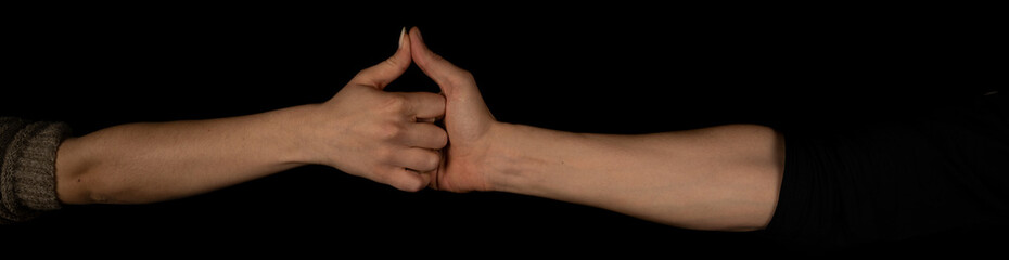 Man and woman, finger wrestling isolated on the black background. Panoramic shot. Copy space for text message. Panorama banner.