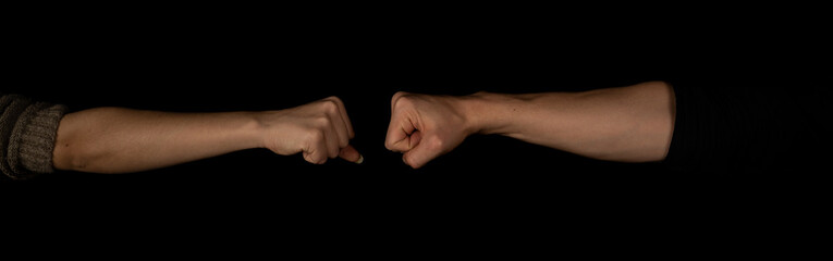 Man and woman fist to fist isolated on the black background. Panoramic shot. Copy space for text message. Panorama banner.