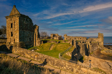 Fototapeta na wymiar St Andrews castle Ruins with blue sky and streaky clouds at sunset, located in fife, Scotland.