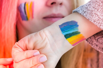 Rainbow LGBTQ flag painted on hand and cheek. Support for lgbt community. Honour of pride month....