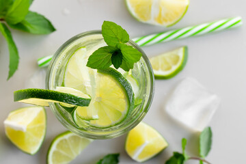 Fresh homemade cocktail with lime, mint and ice on a white table, close up, top view