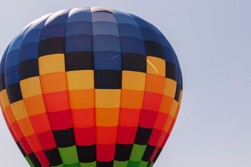 Blue, orange, yellow, green are the colors of a huge parachute. The parachute is in the air.
