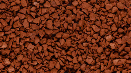 Instant coffee granules lying on a flat surface, panorama.
