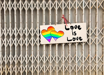 White paper which has hearts in rainbow colours drawing and texts 'We support homosexual' hangin on the steel folding doors, concept for supporting and encouraging 'LGBTQ+' communities over the world.