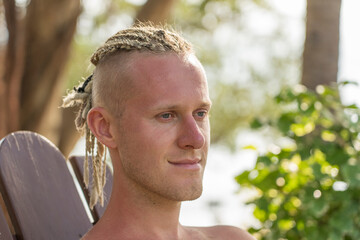 Portrait of a young guy with dreadlocks on his head in nature. Close up