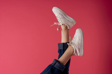 inverted female legs in white sneakers fashion studio pink background