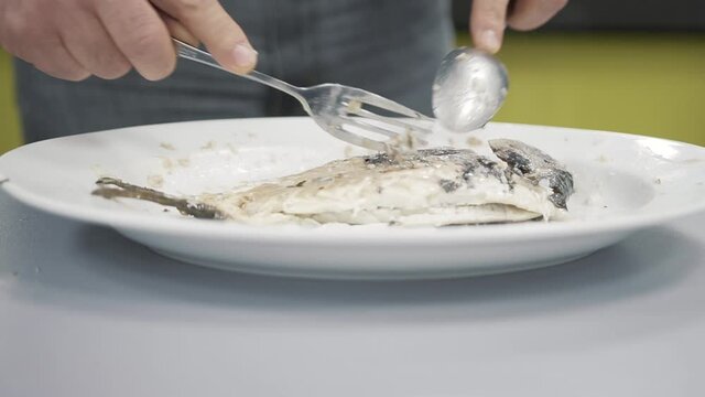 Skillful waiter removing bones from freshly cooked fish in close up view