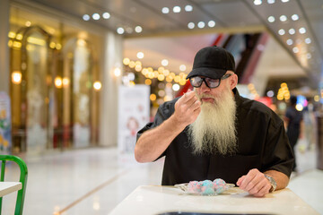 Man sitting in shopping mall and eating ice cream