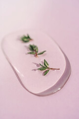 A drop of cosmetic gel with thyme on a pink background.