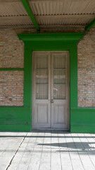 Puerta antigua de madera blanca y marco de un llamativo color verde