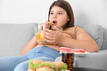 Overweight girl eating unhealthy food at home