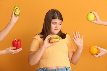 Displeased overweight girl with unhealthy burger refusing healthy food on color background