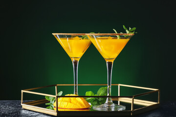 Tray with tasty mango margarita and mint on dark color background