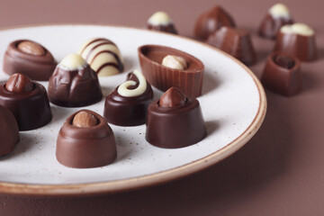 Plate with tasty chocolate candies on color background, closeup