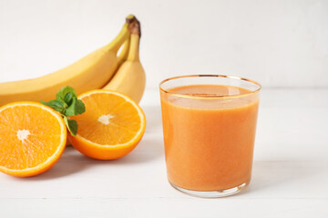 Glass of healthy smoothie with fruits on white wooden background