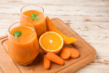 Glasses of healthy smoothie and ingredients on light wooden background