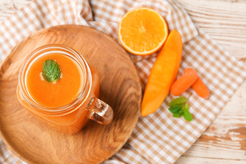 Mason jar of healthy smoothie and ingredients on light wooden background