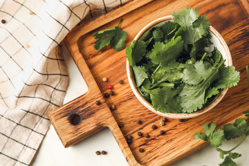 Board with fresh cilantro and peppercorns on table