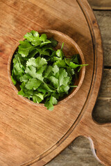 Bowl with fresh cilantro on wooden background