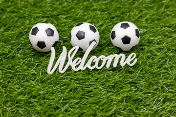 Obraz premium Welcome sign with soccer balls are on green grass