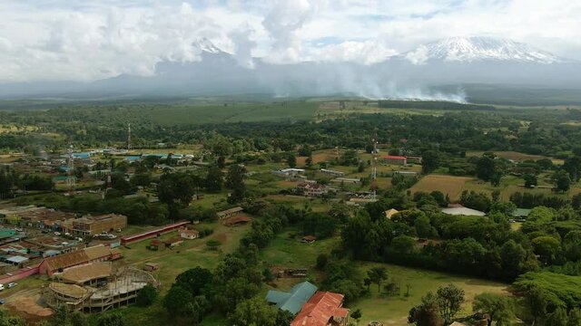 Aerial view over a town, grassfire burning on the east African countryside - reverse, drone shot