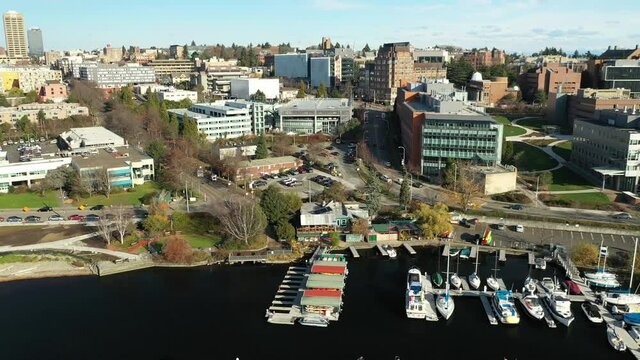 Cinematic aerial trucking drone footage of Fritz Hedges Waterway Park, University of Washington with surrounding commercial and residential area, dormitories and classroom buildings in the background
