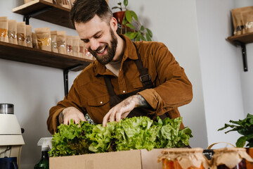 Happy mid farmer man in apron selling fresh produce