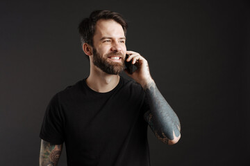 Bearded happy man smiling and talking on cellphone
