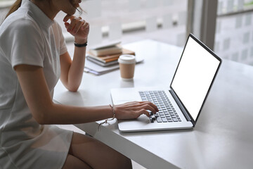 Cropped shot of businesswoman sitting in minimal cafe and working with laptop computer.