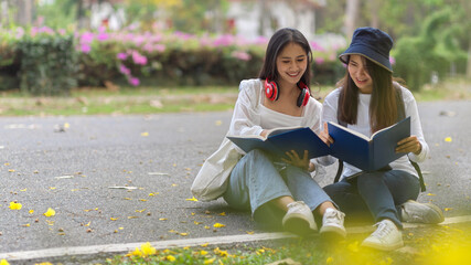 Cropped shot of two pretty female students outdoor studying together in campus ground