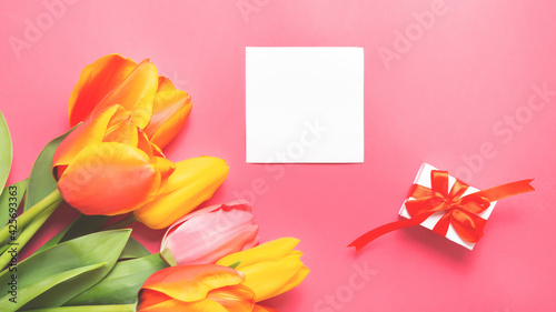spring bouquet flowers tulips, gift box and blank card on the pink background. Mother's Day, Birthday, Valentine's Day, Women's Day, Celebration Concept. Top view, flat lay.