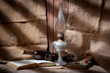 A vintage kerosene lamp covered in dust and soot, shot against a background of wood panels and burlap.