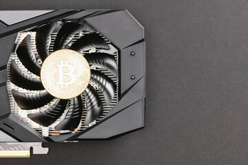 Silver Bitcoin coin on a Black video Card on a gray background. Crypto currency, close up. Bitcoin mining concept