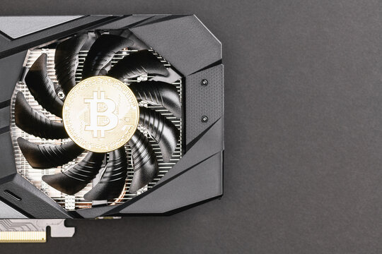Silver Bitcoin coin on a Black video Card on a gray background. Crypto currency, close up. Bitcoin mining concept