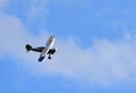 Vintage Gloster Gladiator aircraft in flight with cloud and blue sky