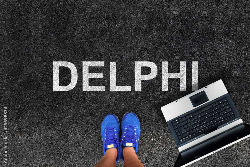 Poster delphi programming language. man legs in sneakers standing next to laptop and word delphi