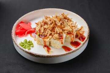 Set of sushi rolls with soy and wasabi sauce. Served on a white plate over black background.