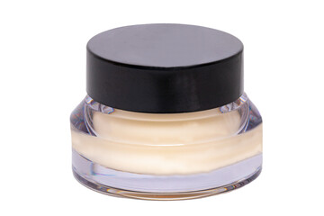 Closeup of an closed glass cosmetic jar with a moisturising white cream for the face isolated on a white background. Beauty and make-up products. Macro.