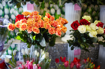Obraz na płótnie Canvas Blurred image of bouquet of fresh roses and tulips in flower shop. Lot of multicolored roses and tulips bouquets