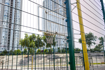 Obraz na płótnie Canvas Basketball court from behind fence. Basketball hoop in the city park. Selective focus, blurred background