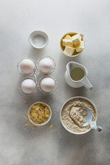 Obraz na płótnie Canvas Baking ingredients - raw eggs, milk, soda, butter, flour, almond petals, top view