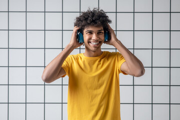 African american young guy in earphones smiling and looking contented