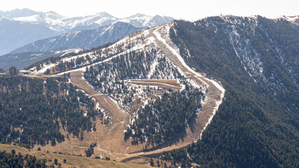 ski slopes in the mountain landscape, running out of snow at the entrance of the spring in the Catalan Pyrenees of Andorra.