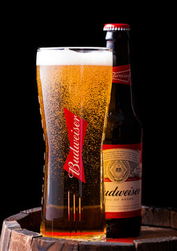 LONDON, UK - APRIL 27, 2018: Glass bottle and original glass of Budweiser original beer on top of old wooden barrel.