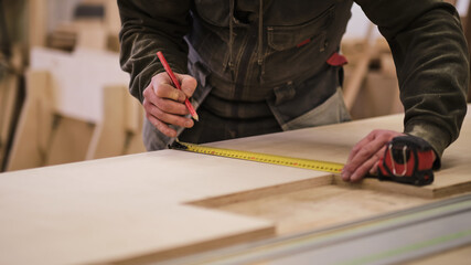 Close up. Carpenter holding a measure tape on the work bench. Woodwork and furniture making...