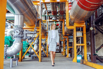 Smiling blond female power plant owner walking around and checking on machinery.
