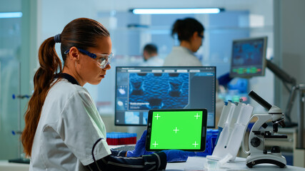 Medical research scientist working on tablet with green screen mock up template in applied science...